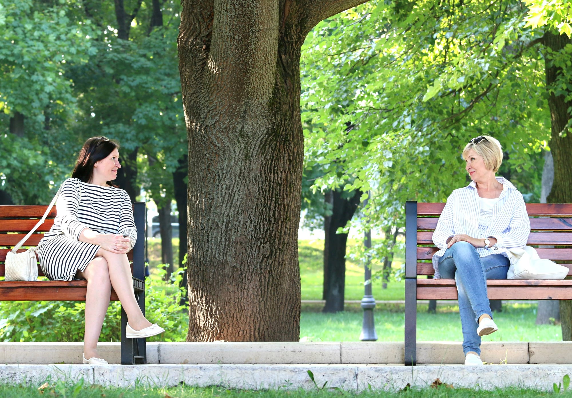 Picture of two women sitting in a park on separate benches about to talk